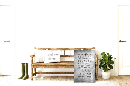 A distressed and grunge-finished Christian Metal Wall Decor features 1 Timothy 4:12, leans against a wooden bench.
Photo courtesy of Honeycomb Proverbs