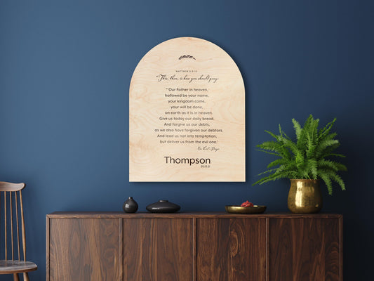 Wood arched The Lord's Prayer Plaque and Family Name sign, Verses of Matthew 6:9-13 are centered in stanza format with a family name "Thompson" beneath. A decorative botanical motif accents the top of the plaque.