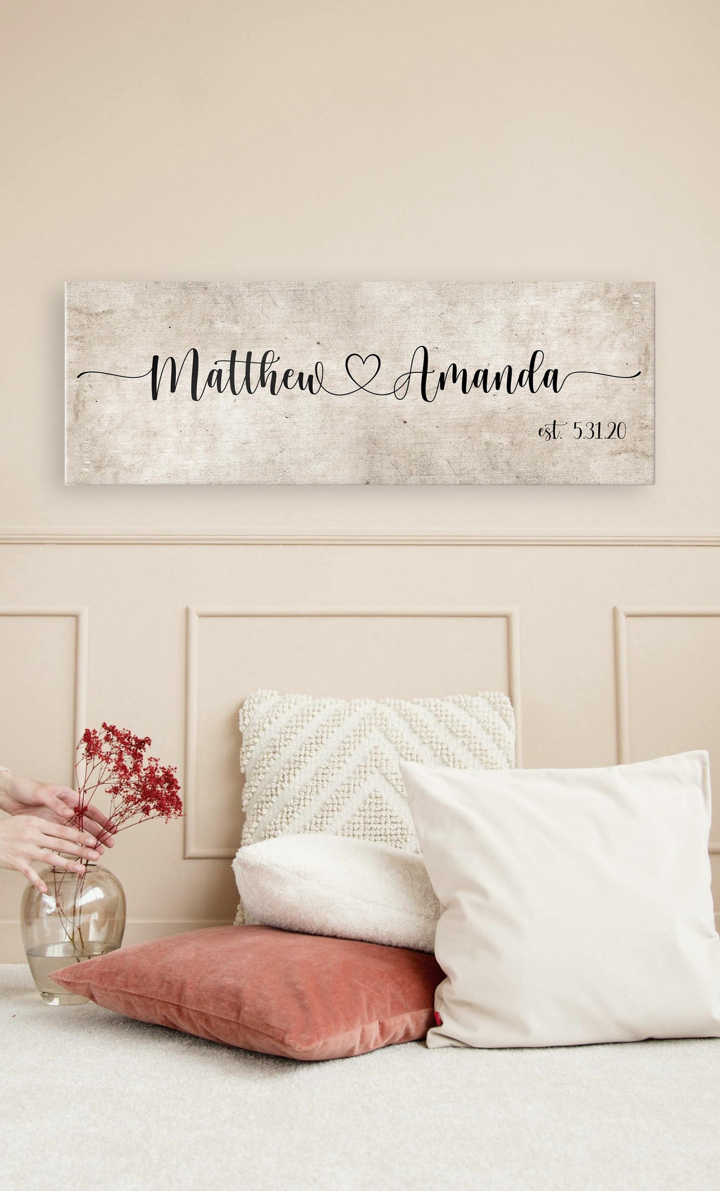 rustic cotton canvas name sign, with 2 first names connected by a heart in a whimsical and playful typeface. A personalized name sign on vintage cotton hangs on wall above bench in entry of home.