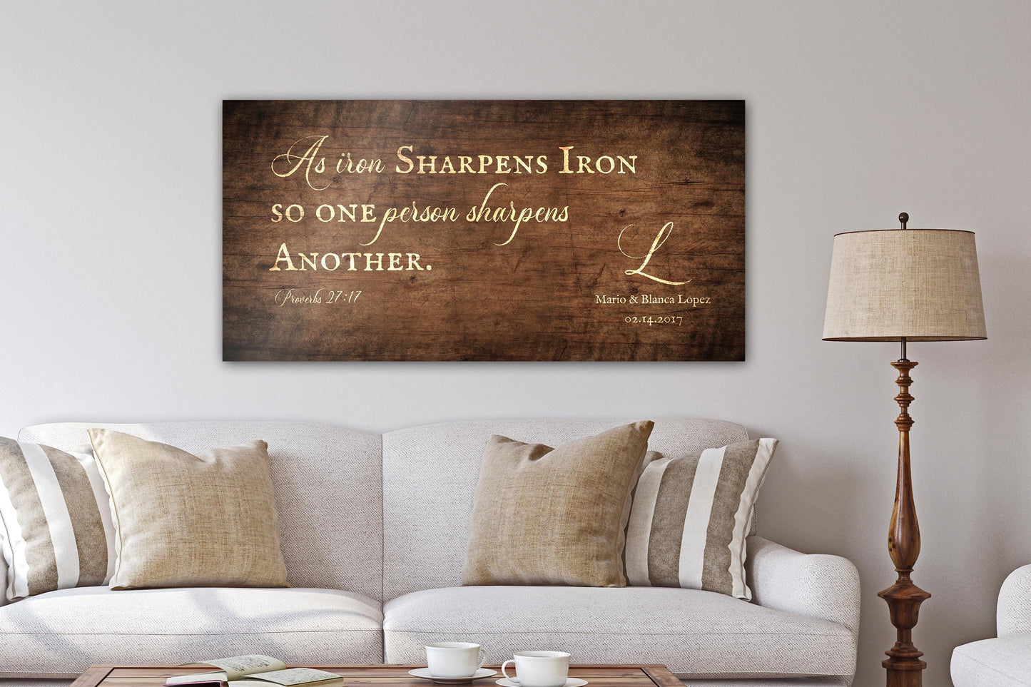 A handcrafted and personalized rustic wooden sign hangs above a linen sofa in "Stained Birch" finish - one of four finish options. The bible verse, "As iron sharpens iron; so one person sharpens another" as well as the names and established date of the recipients' are included on this handcrafted rustic wall decor.

Courtesy of Honeycomb Proverbs