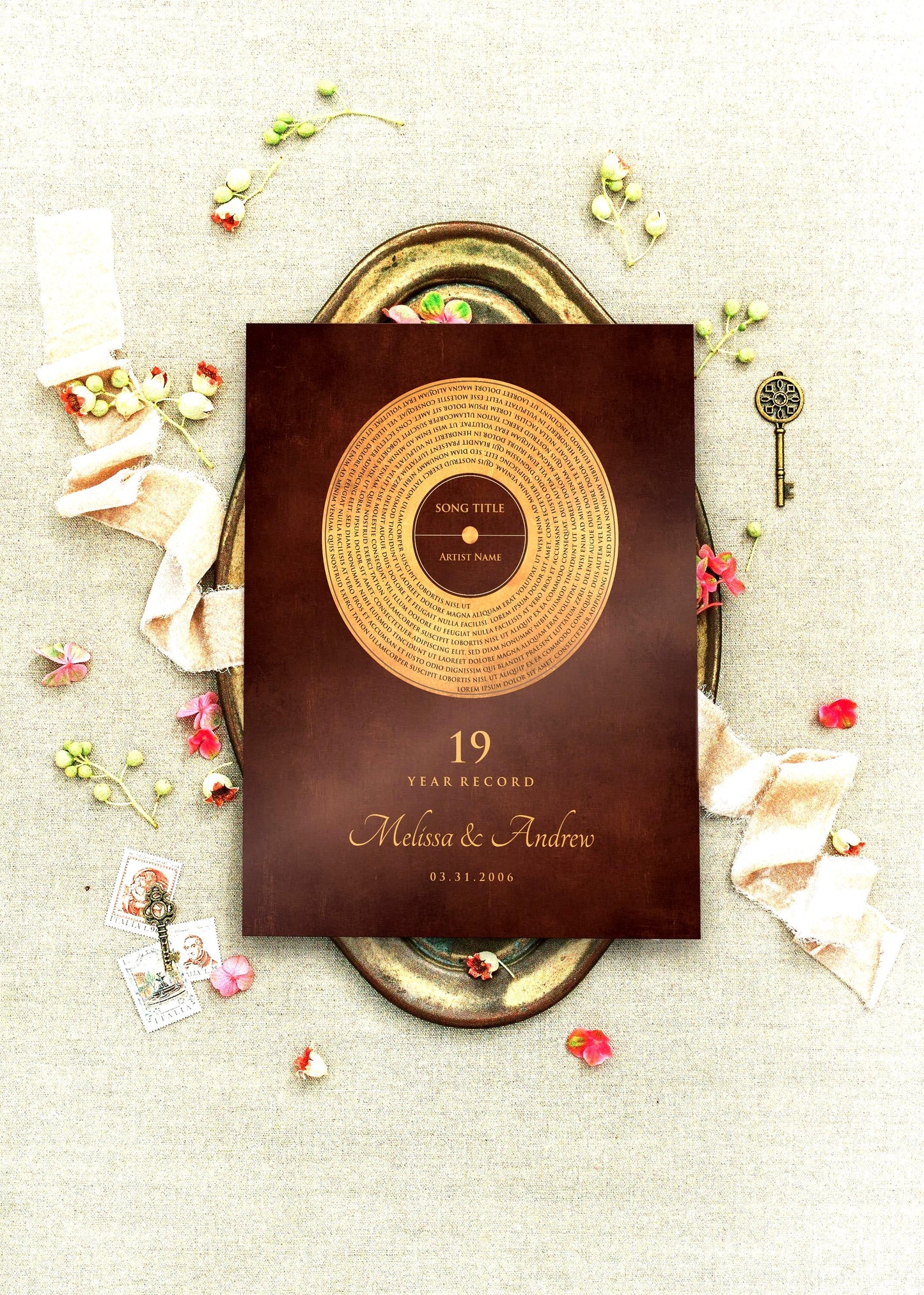 Custom Oil-Rubbed Bronze Anniversary Record Plaque is center frame, viewed from romantic, aerial perspective. It's set on a brass tray and surrounded with sprigs of poppies, and with a couple of antique keys on a linen cloth.  The plaque is set on a burnished bronze finish - record motif occupying an aged bronze finish with an overlay of the song lyrics of choice, with credit on the label. Below is the anniversary year, couple's names and union date.   Photo courtesy of Honeycomb Proverb