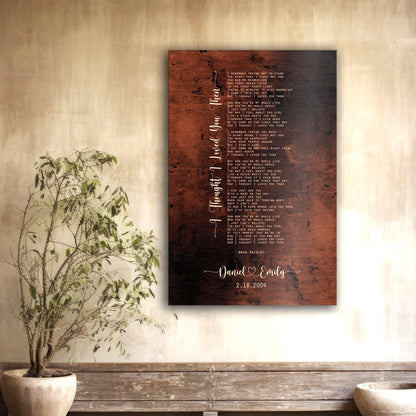 Metal Custom Song Lyric Wall Art shown is the Burnished Bronze Anniversary Song Portrait with the words "I thought I loved you then" inscribed in a whimsical calligraphy and custom song lyrics in a stanza format.
The names David and Emily sit beneath the song lyrics, center bottom, also in a whimsical font style and connected by a heart. The date 2.15.2004 indicates this is a 22 year anniversary gift.

Photo courtesy of Honeycomb Proverbs