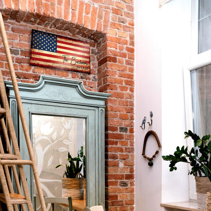 Rustic wood American flag sign hangs over door threshhold, personalized with "The Thompsons - Est. 2019". Sign mounted on red brick wall.

Photo courtesy of Honeycomb Proverbs