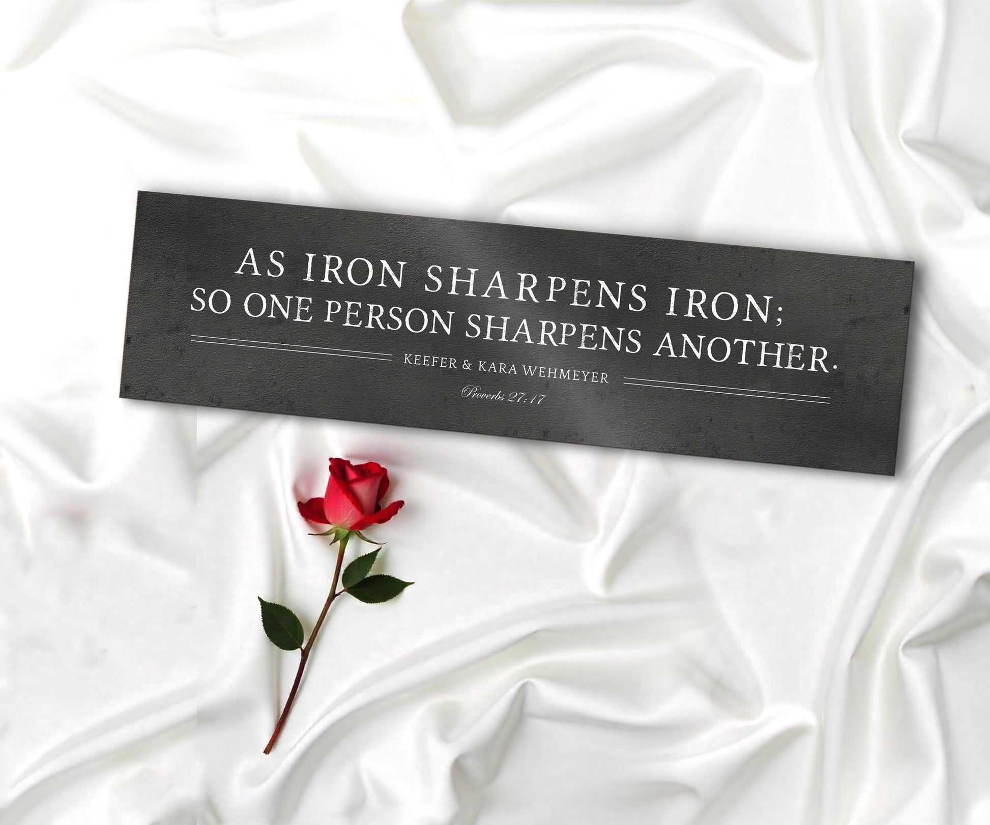 As iron sharpens iron so one person sharpens another is inscribed on a wide format metal plaque and the names Sara and Alex and their union date is under the bible verse.   Photo courtesy of Honeycomb Proverbs