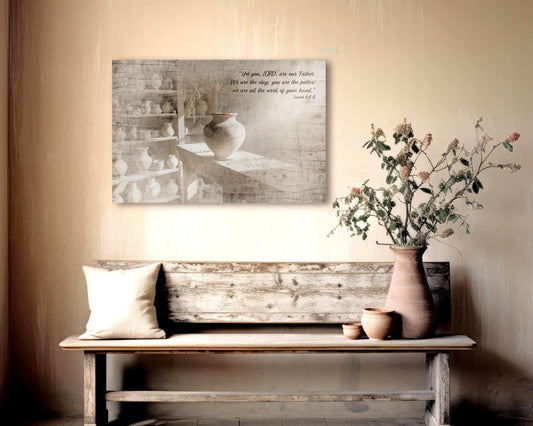 Wood Christian Wall Art, aged and weathered wood, image of a clay pot in a workshop and the bible verse Isaiah 64:8 "Yet you, LORD, are our Father. We are the clay, you are the potter; we are all the work of your hand" is inscribed in a casual calligraphy on the upper right corner.