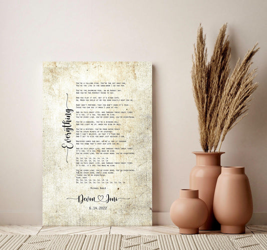 Wedding Song Art printed on vintage canvas and leaning against a wall. Cancas is beigewith song lyrics and personalized with the couples first names connected by a heart and wedding date