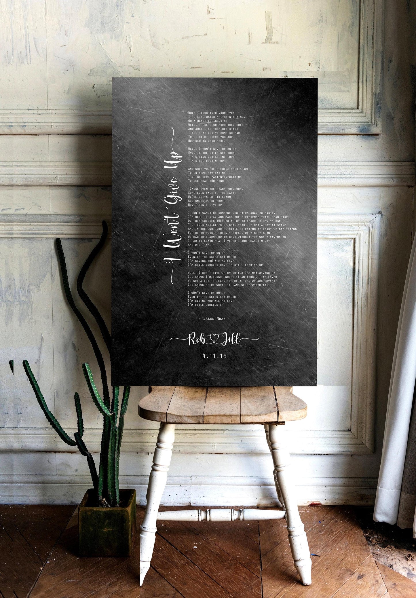 A distressed metal song plaque personalized with the names "Rob & Jill" and the date "4.11.16", sits on a chair.