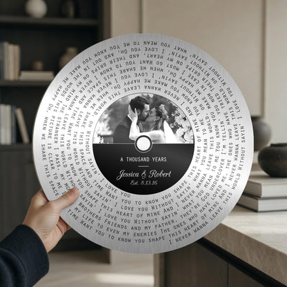 Round tin song lyrics record held in hand, showing the couple photo label and spiral lyrics