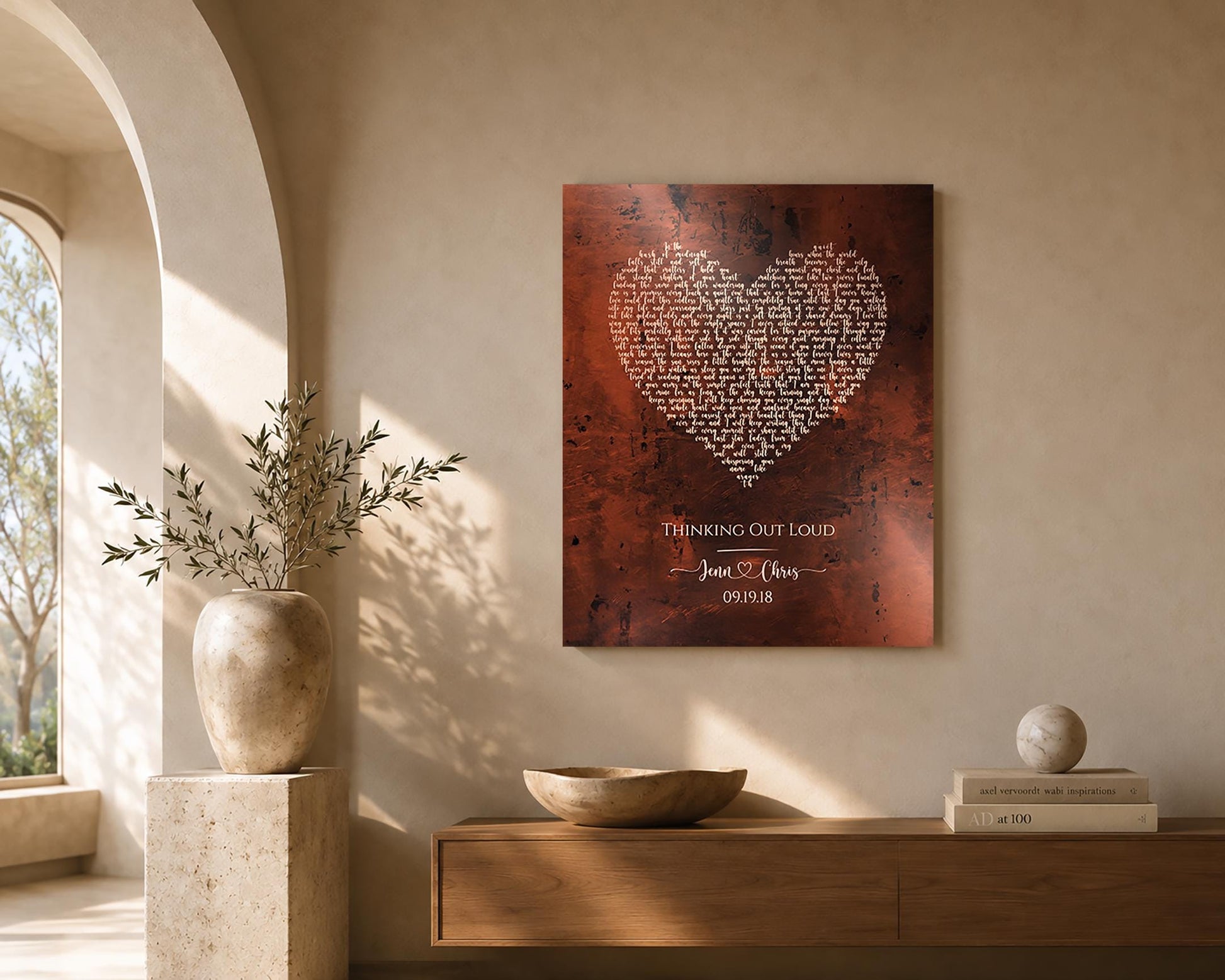Bronze artwork with custom song lyrics, and a song title. This is a bronze anniversary wall plaque designed for first dance lyrics or wedding songs and also features 2 first names joined by a heart motif, and a union date. It's displayed above a table, mounted onto a wall.